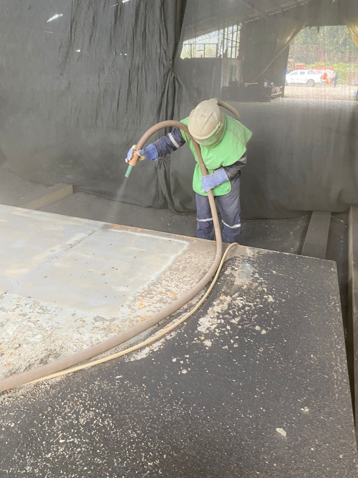 Operario granallando una superficie metálica